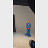 Woman wearing a blue and turquoise dance costume moving up and down.