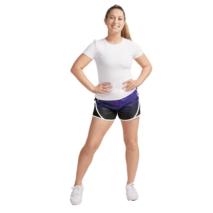 Model wearing S‑Line paneled performance shorts in black with white piping trim and purple geometric panel, mid-rise fit with elastic waistband—styled for dance, drill, or color guard